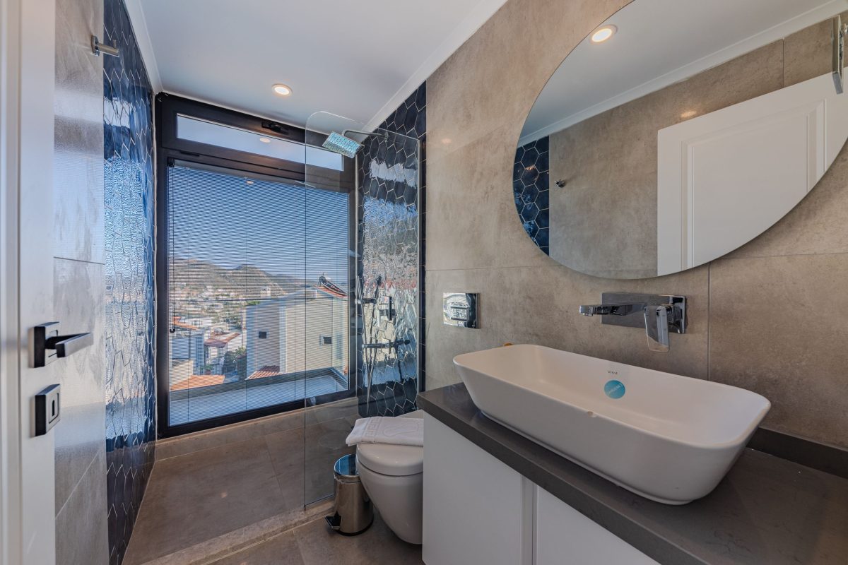 Explore a contemporary bathroom featuring luxury fittings and a scenic window view.